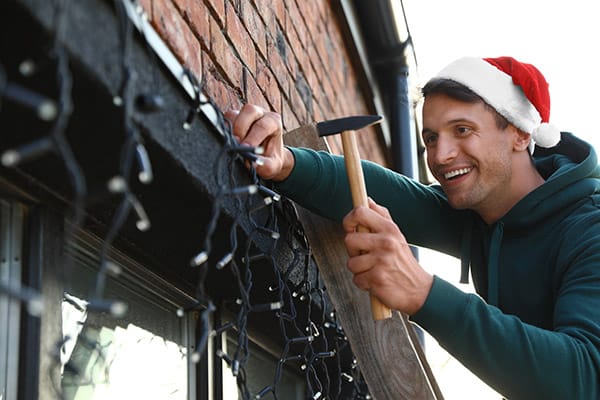 man-installing-Christmas-lights-around-windows-outdoors.jpg